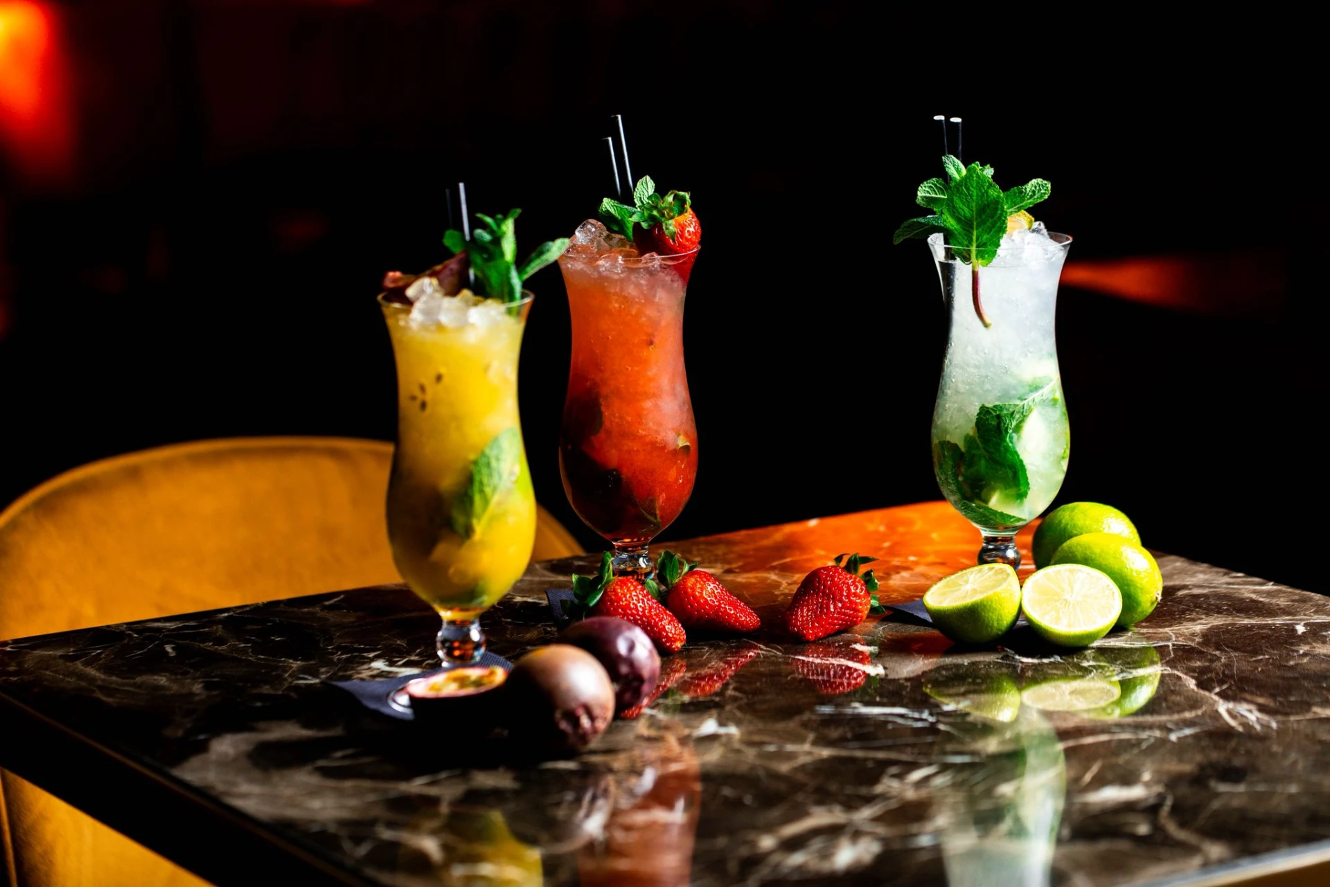 Three fruit cocktails garnished with mint on a marble bar top
