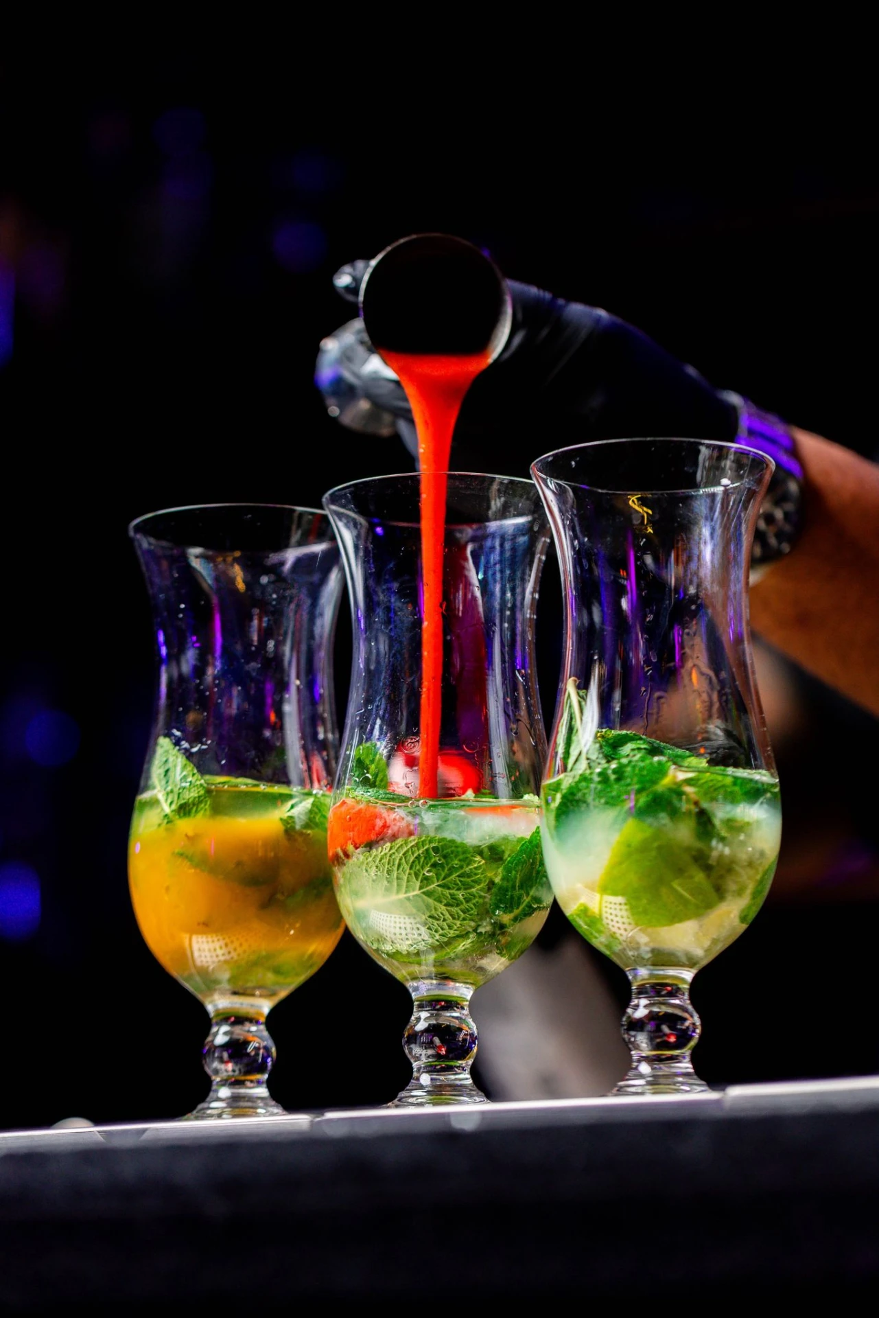 Bartender pouring a strawberry cocktail into glasses